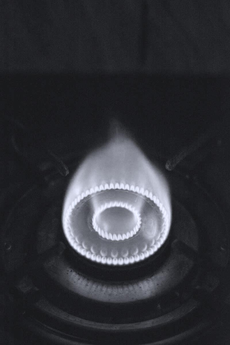 A black and white photo of a flame coming from a gas stove burner.